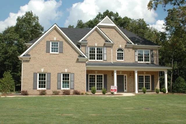 Luxury real estate agent holding a tablet and pointing at a high-end home